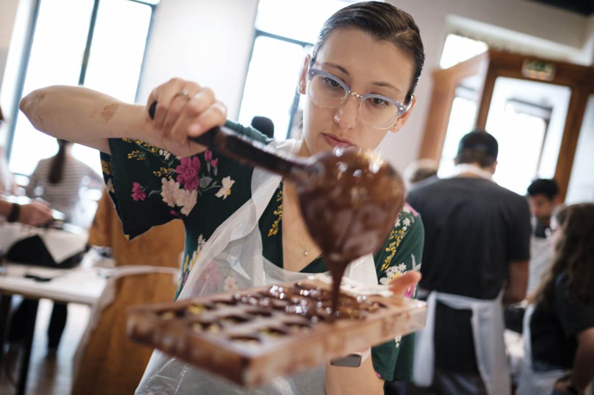 person filling up a chocolate mold with chocolate at belgian chocolate workshop in Bruges